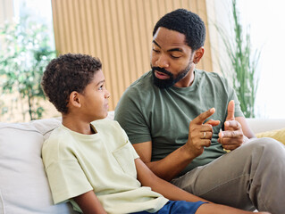 Portrait of a happy teenage boy son talking to his father at home. Sharing secrets and having fun,...