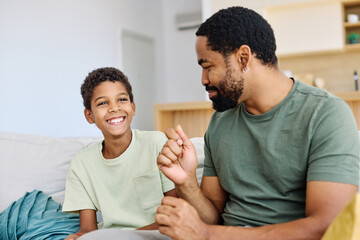 Portrait of a happy teenage boy son talking to his father at home. Sharing secrets and having fun, support and parenthood concept