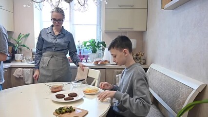 Middle-aged Caucasian woman cooking burgers with her two sons. 