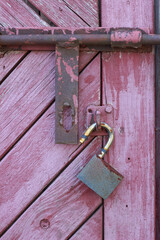 Old pink wooden door with a rusty lock and bolt