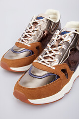 Varicoloured glossy leather high thick soled women's fashion sneakers, sports shoes, boots for female in isolated on white background. Shimmering footwear, training basketball shoes. Above view