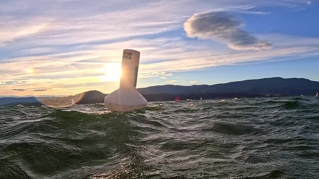 Marker buoy in choppy water with mountain background at sunset in Lake Okanagan