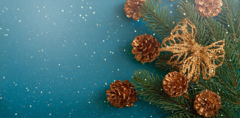 Christmas banner background with set of decorative branch, golden bow and cones for tree decoraton. New Year winter holidays concept with decor in blue and gold colors and copy space, top view.