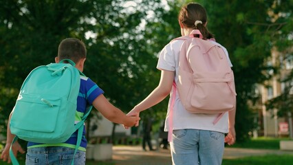 Happy children running down street to school. Boy girl children walking with backpacks from school home. Cheerful children, brother and sister on street. Children with backpacks heading to school