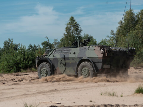 Fennek reconnaissance vehicle creating dust cloud while moving through sandy training area