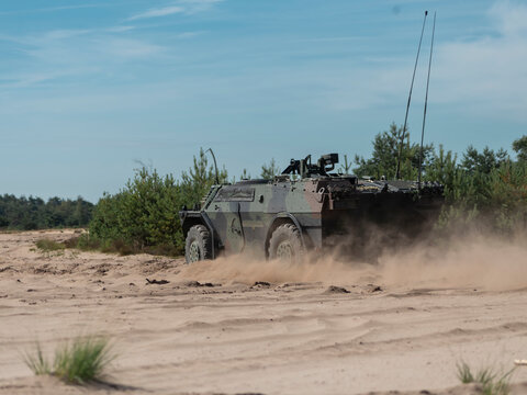 Fennek reconnaissance vehicle performing tactical maneuvers in dusty field conditions