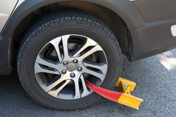 Yellow and red wheel clamp on car tire.