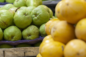 Fresh green guavas stacked at a market with yellow passion fruits in the foreground.