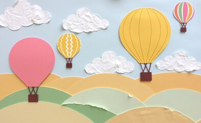 Obraz premium Vibrant hot air balloons ascend over a landscape of rolling hills under a sky dotted with fluffy clouds, creating a whimsical scene.