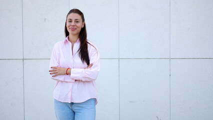 Professional businesswoman crossing arms, leaning against white tiled wall, expressing corporate...
