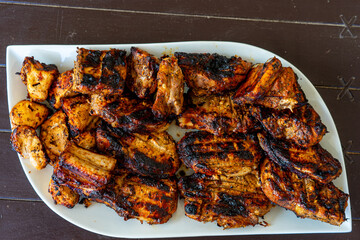 A delicious plate of assorted barbecue meats, including pork, chicken, and beef, freshly grilled and served hot for a hearty meal.
