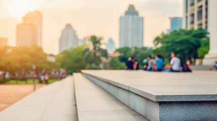 People relax on steps in a city park as sunset illuminates the skyline