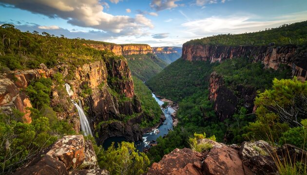 High angle view of a vibrant canyon landscape, showcasing a rushing waterfall cascading down dramatic cliffs.