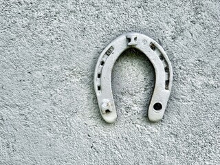 Old metal horseshoe hanging on concrete wall as symbol of good luck