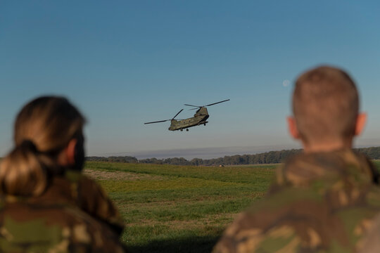 Single Chinook helicopter in flight with military personnel observing during daylight training operations - Powered by Adobe