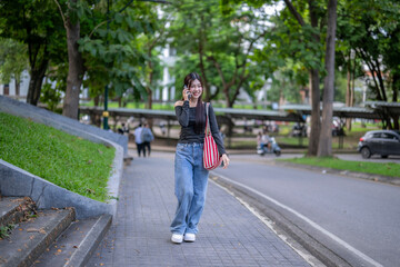 Young woman walking and talking on phone in park