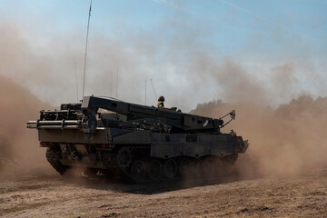 Military engineering vehicle creating dust cloud during field operations and maneuvers