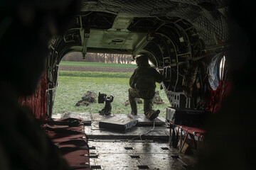 Interior view of military helicopter with soldier positioned at open cargo ramp