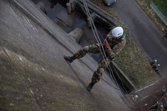 Soldier with white helmet rappelling down building during urban tactical training
