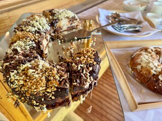 Chocolate cake with nut topping and slices served on wooden board