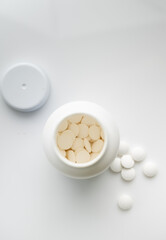 Close up of light Round Pills in White Plastic Bottle