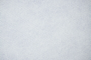 Close-up texture of white nonwoven fabric with small dotted pattern design
