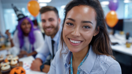 Obraz premium Joyful Office Halloween: A smiling woman with colleagues and festive decorations in a business setting.