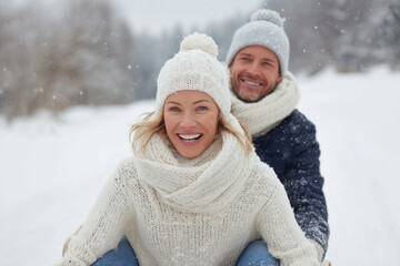 joyful couple riding sled together in snowy forest surrounded by thick white snow