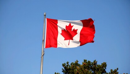 A vibrant Canadian flag billows freely in a clear, bright blue sky.