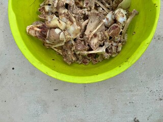 Collection of cooked animal bones placed in a bright yellow plastic bowl on gray background