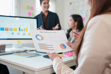 Business team meeting with sales performance chart, diverse professionals discussing data analysis, teamwork, and strategy planning in modern office environment