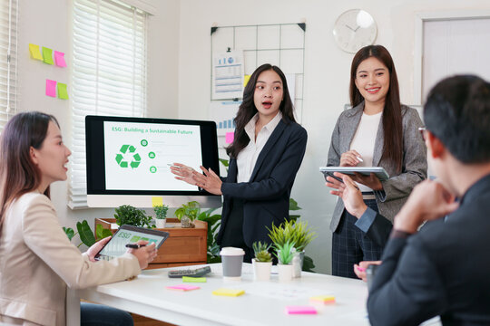 Businesswoman presenting ESG building and sustainable future concept in modern office, diverse team discussing eco friendly strategy, digital tablet, teamwork, green plants, positive atmosphere - Powered by Adobe