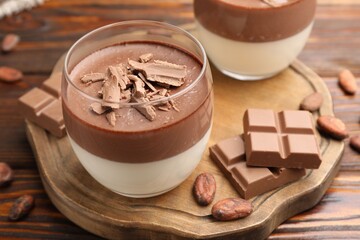 Delicious panna cotta with chocolate and cocoa beans on wooden table, closeup