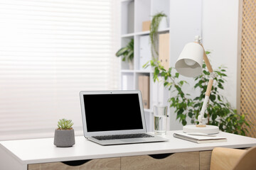 Stylish workplace with laptop and stationery on white table in office