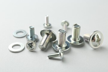 Many different metal bolts on light grey background, closeup. Hardware tool
