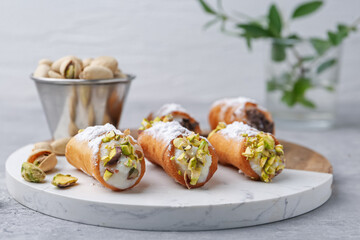 Delicious cannoli with ricotta cheese, pistachios and powdered sugar on light grey table indoors, closeup