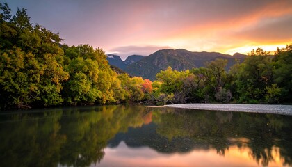 A serene river scene reflects colorful autumn foliage against a backdrop of mountains at sunrise.