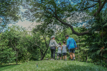 A beautiful moment of parenting. An Asian mother and father guide their two young sons by the hand...