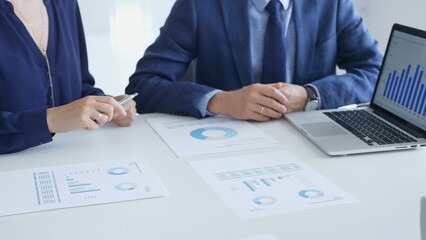 Business auditors reviewing financial data, pointing at laptop charts and discussing documents during collaborative strategy session. Business people and finance