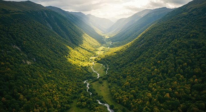 Summer landscape with a panoramic view of green valleys and snow-capped mountains under a cloudy sky