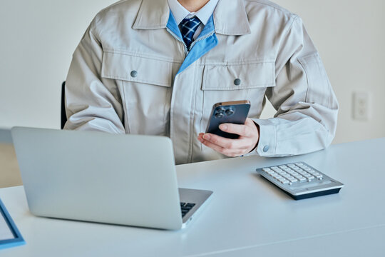 スマホを操作する作業服姿の若い男性