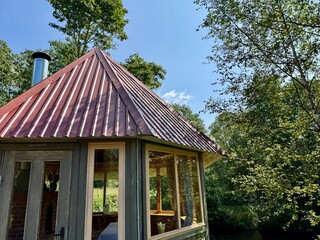 wooden gazebo stands weathered and decaying in an overgrown garden, where nature is slowly reclaim