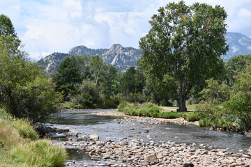Gorgeous Rocky Mountain landscape. Winding river going through a green valley. Large smooth stones in the river.