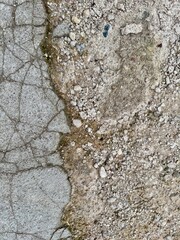 Detailed view of cracked concrete texture with gravel and soil background