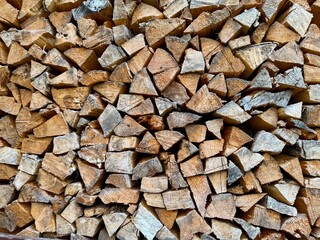 Pile of stacked chopped firewood pieces ready for storage and use in fireplace or stove