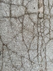 Detailed view of cracked concrete texture with gravel and soil background