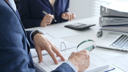 Two professional chartered accountants reviewing financial reports and analyzing data using a...