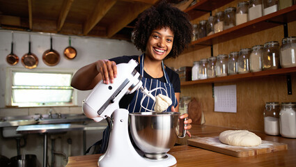 Smiling woman using a stand mixer to make bread dough