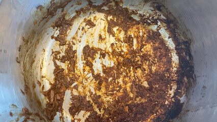 The inside of a dirty pot with burnt food after cooking a meal