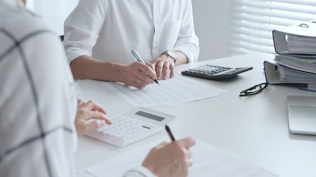 Financial professionals reviewing spreadsheets, working together at modern workspace with calculators, discussing reports. Audit and taxes in business